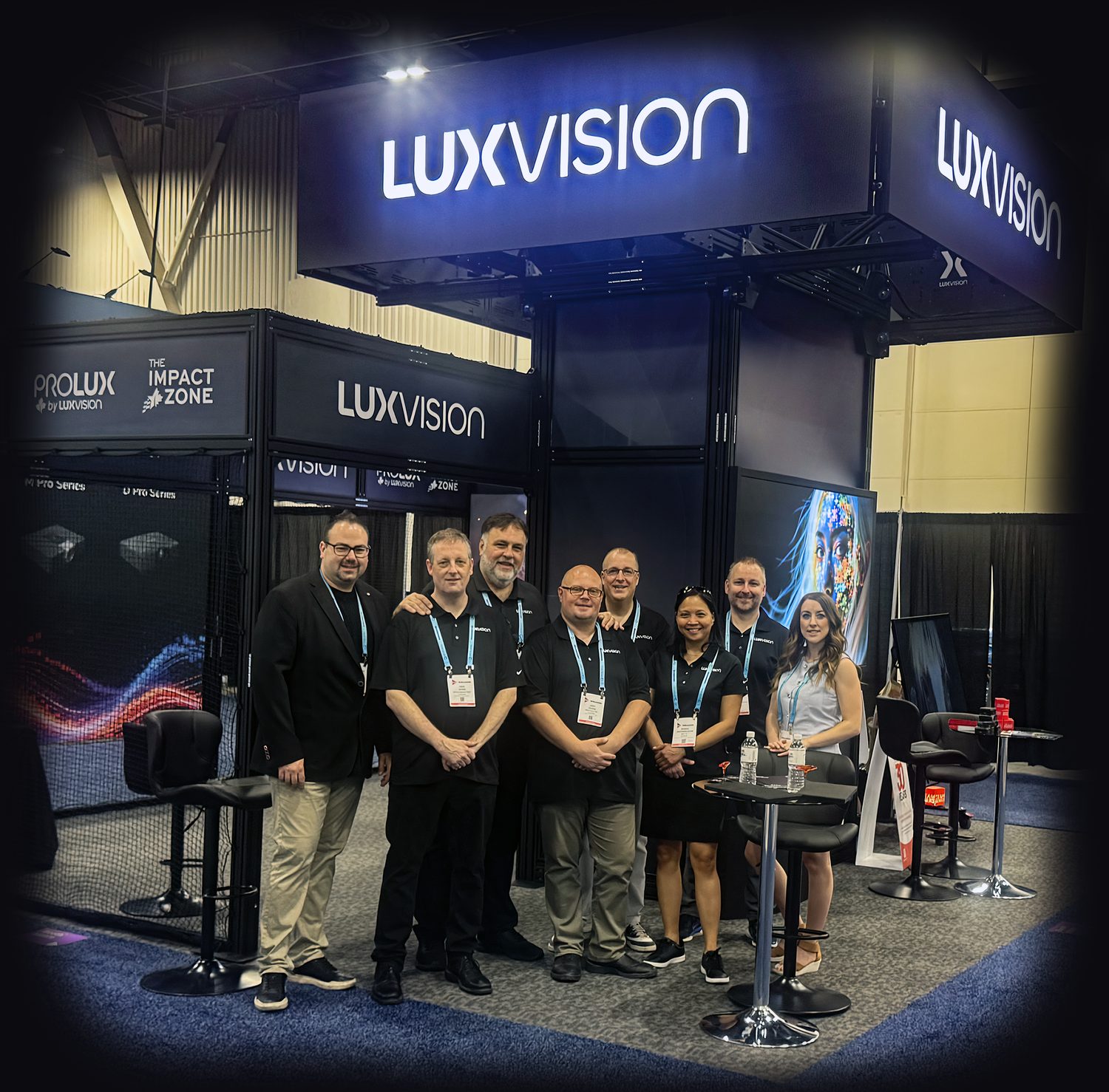 The LUXVISION sales team on the company's stand at InfoComm 2026
                in Las Vegas, standing together in front of the booth's LED wall
                beneath the LUXVISION overhead sign